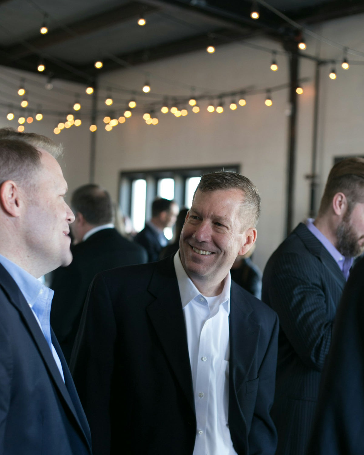 Guests chatting under string lights at a small event