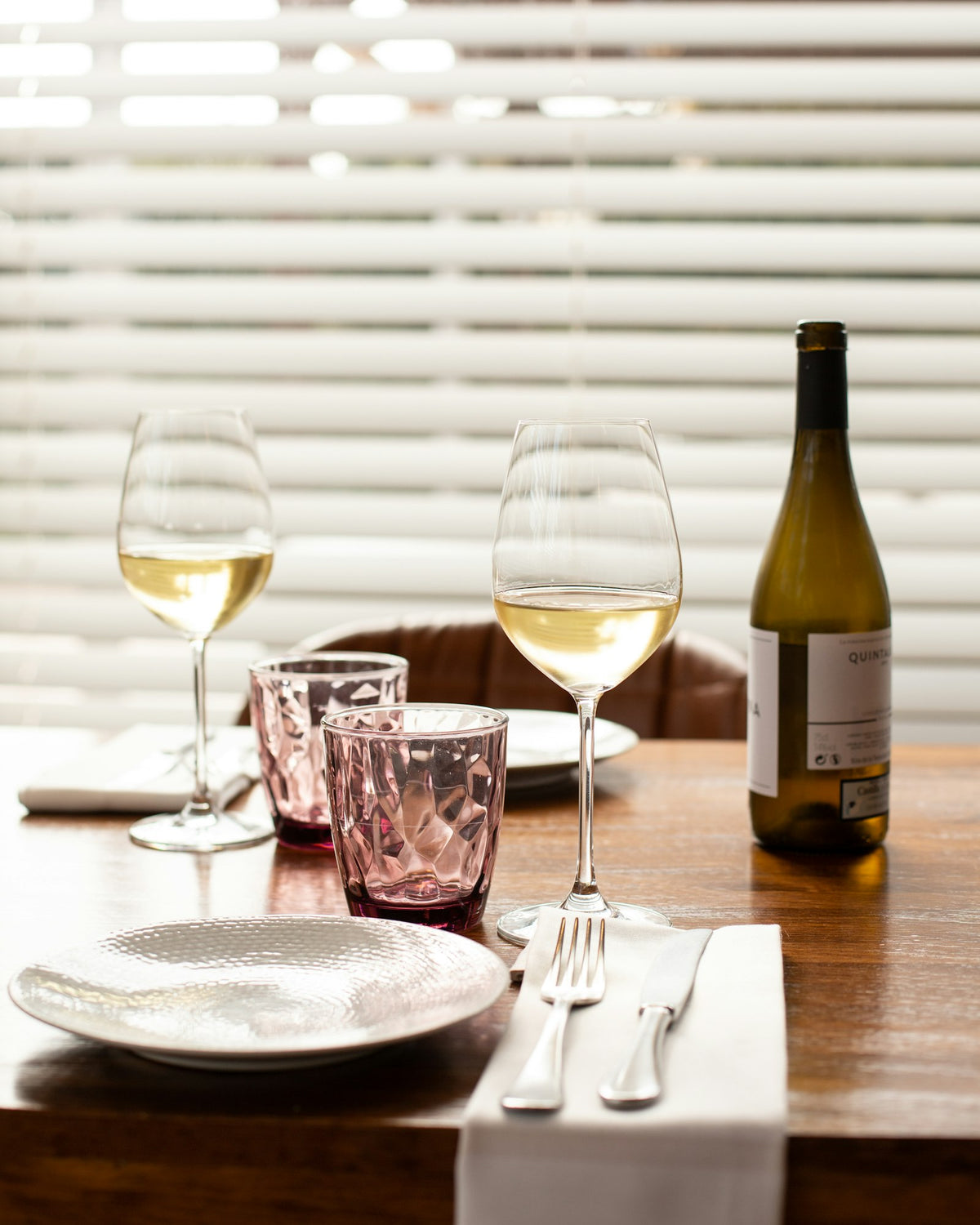 Sunlit restaurant table set with white wine