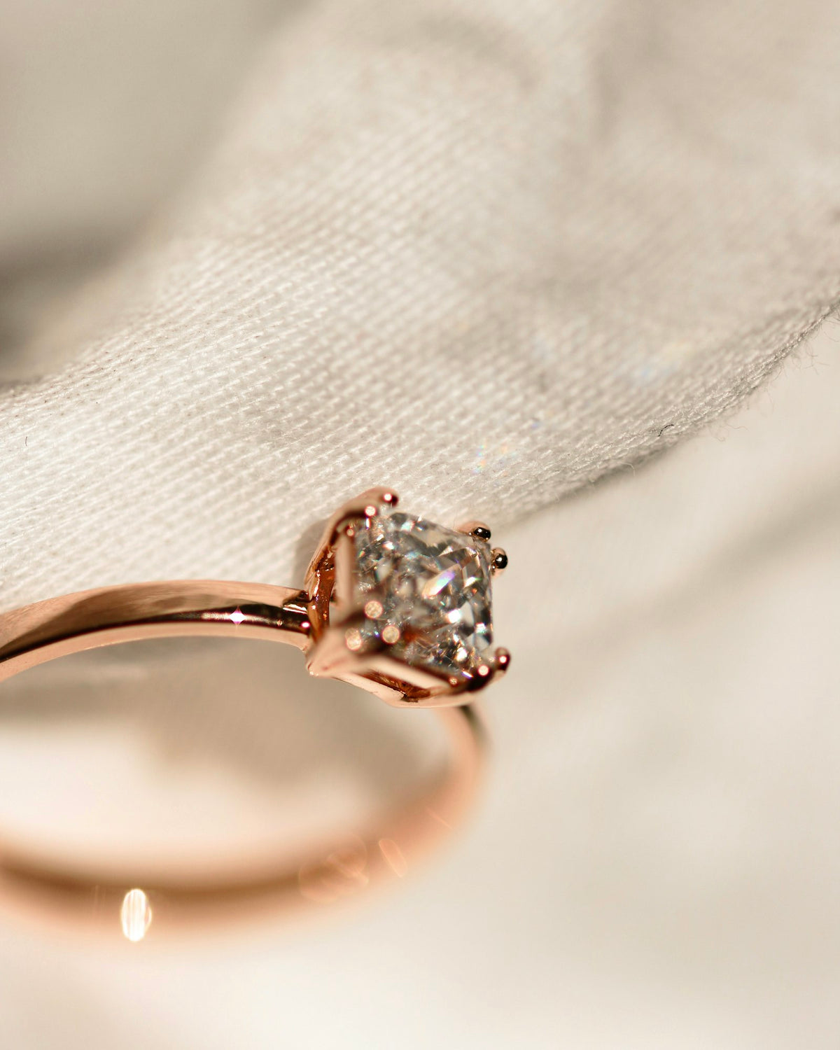 Rose gold diamond solitaire ring on cream linen