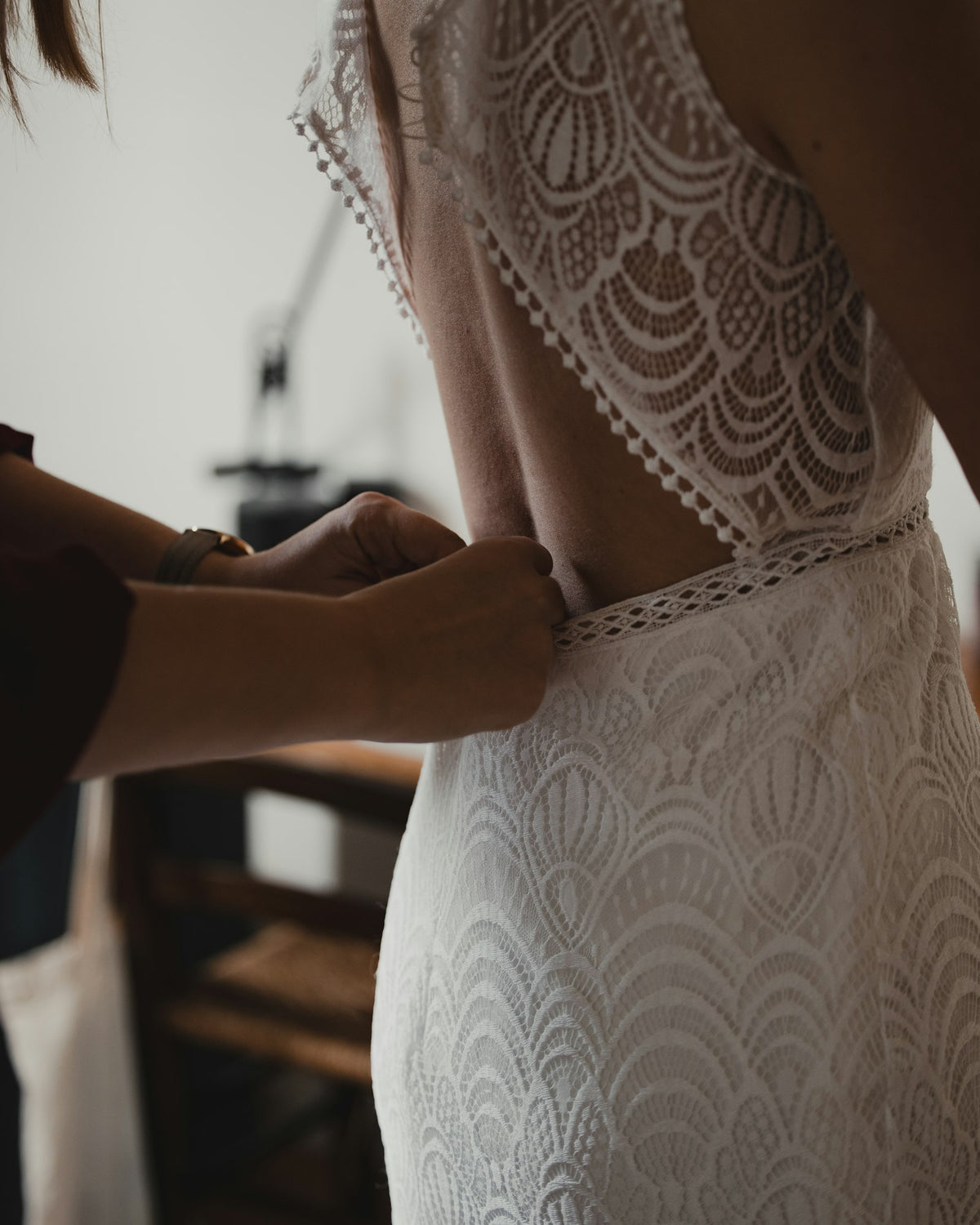 Two people fitting a lace wedding dress