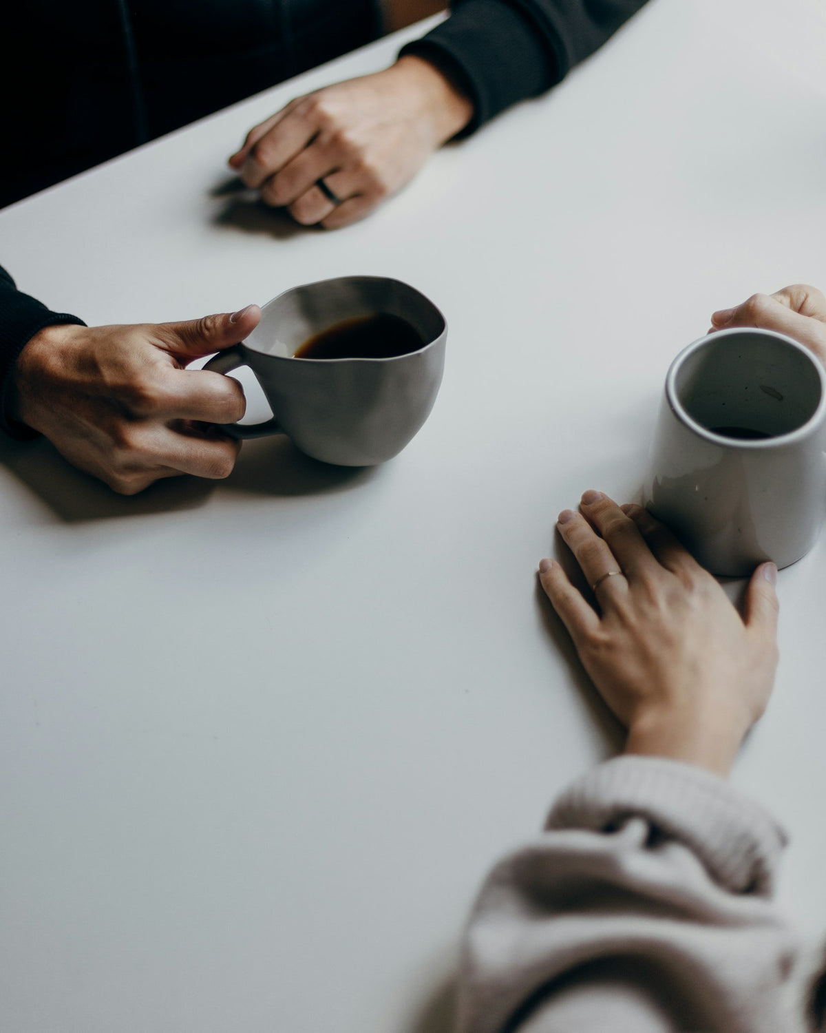 Two people talk over coffee at a white table