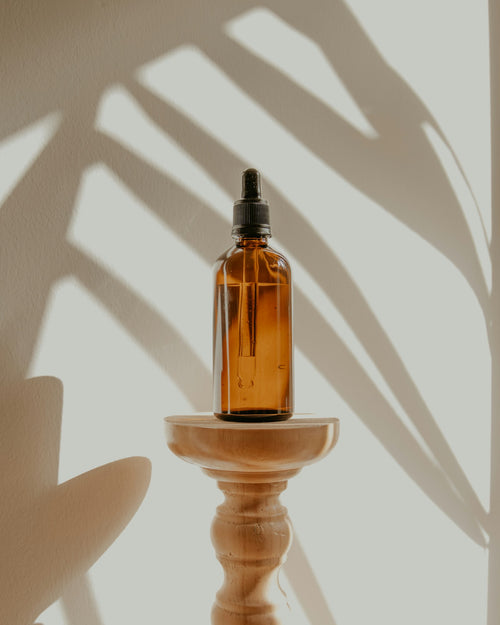 Amber hair-care bottle on a wooden stand in soft light