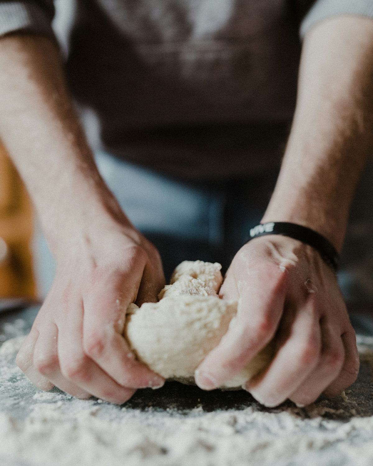 Hands kneading dough on a floured wooden table