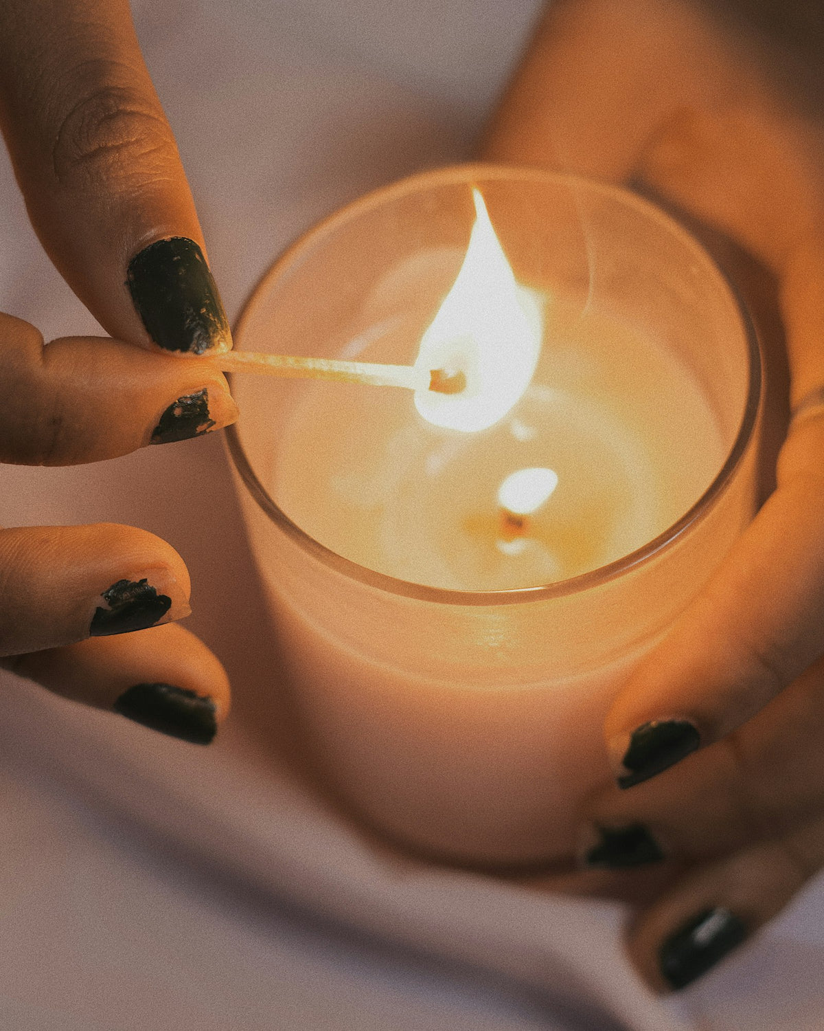 Hands lighting a handmade candle in a glass jar