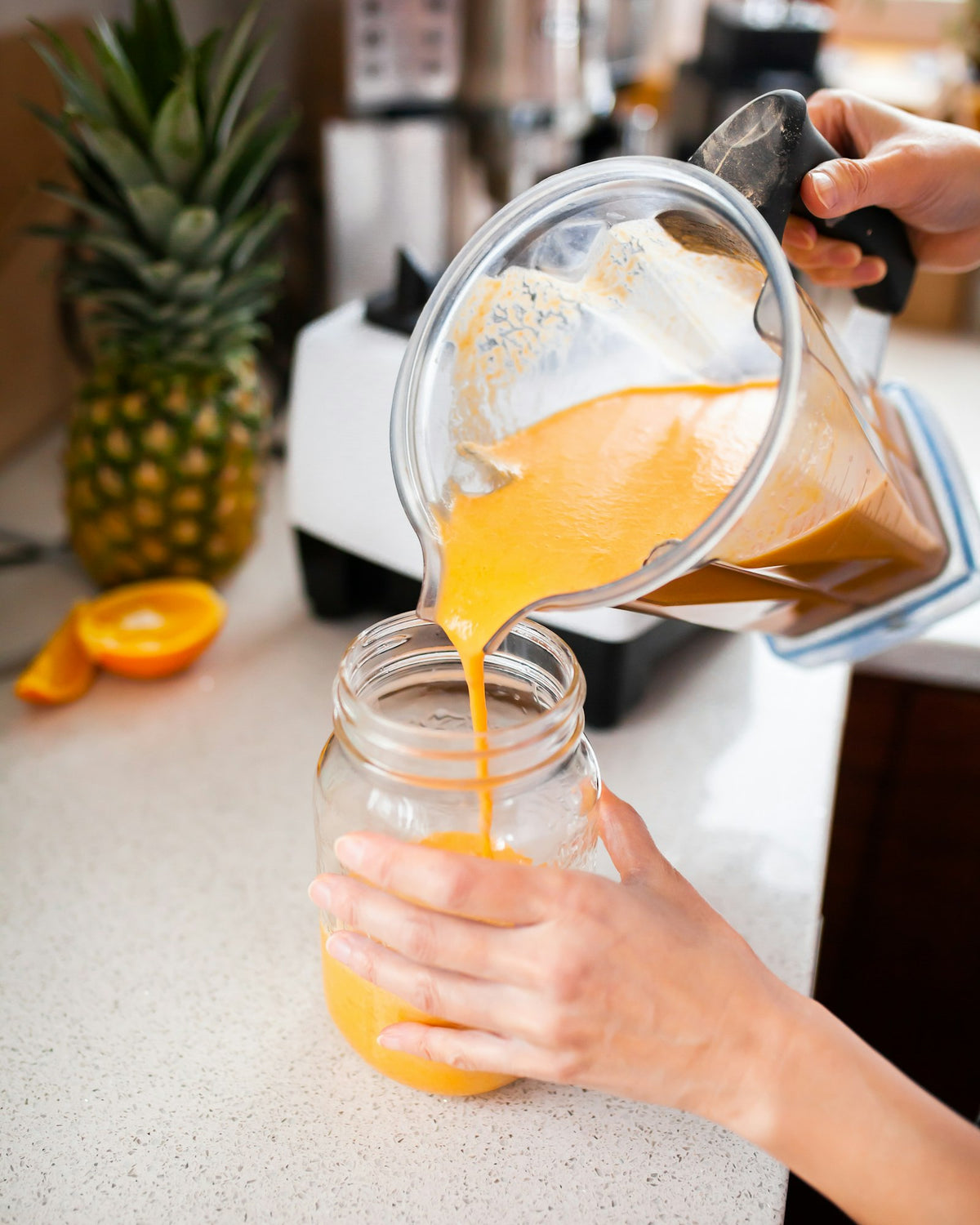 Hands pouring fresh orange juice into a jar