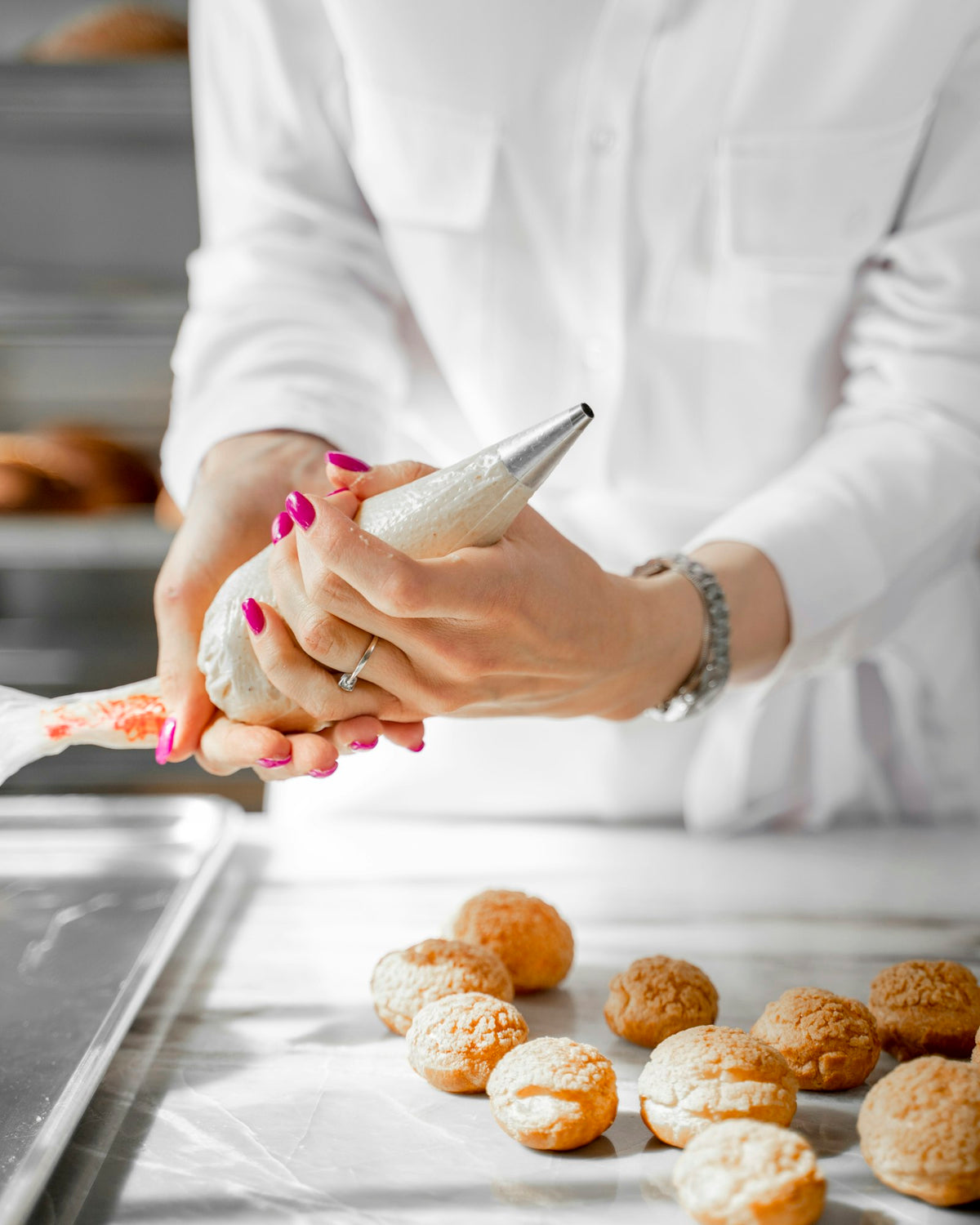 Baker piping cream into choux pastry shells