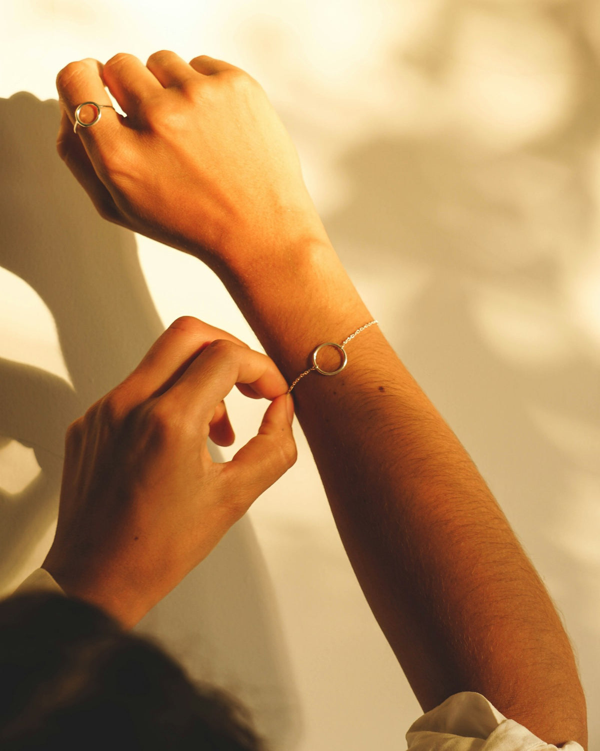 Hands fastening a fine gold bracelet on a wrist