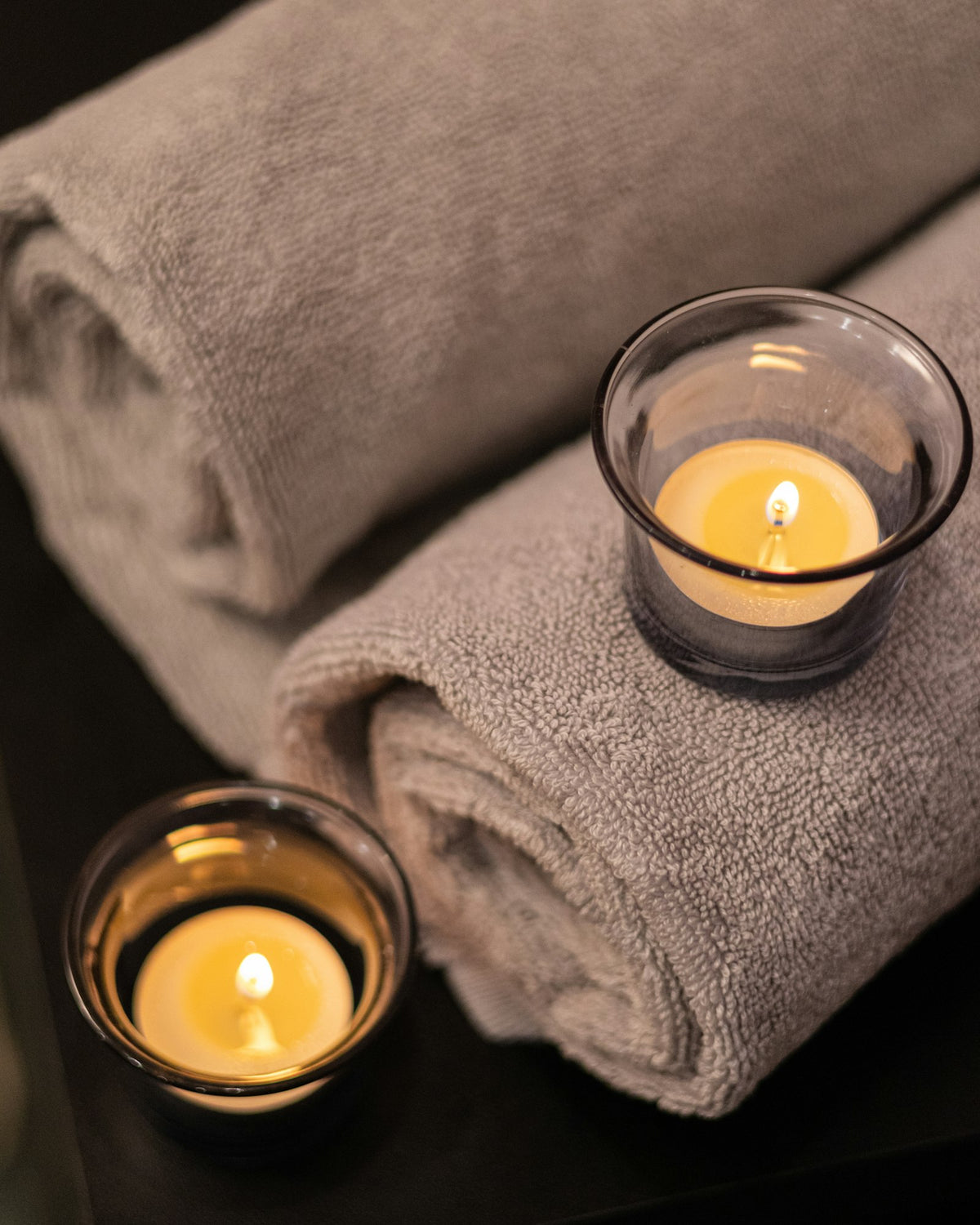 Rolled spa towels beside lit candles