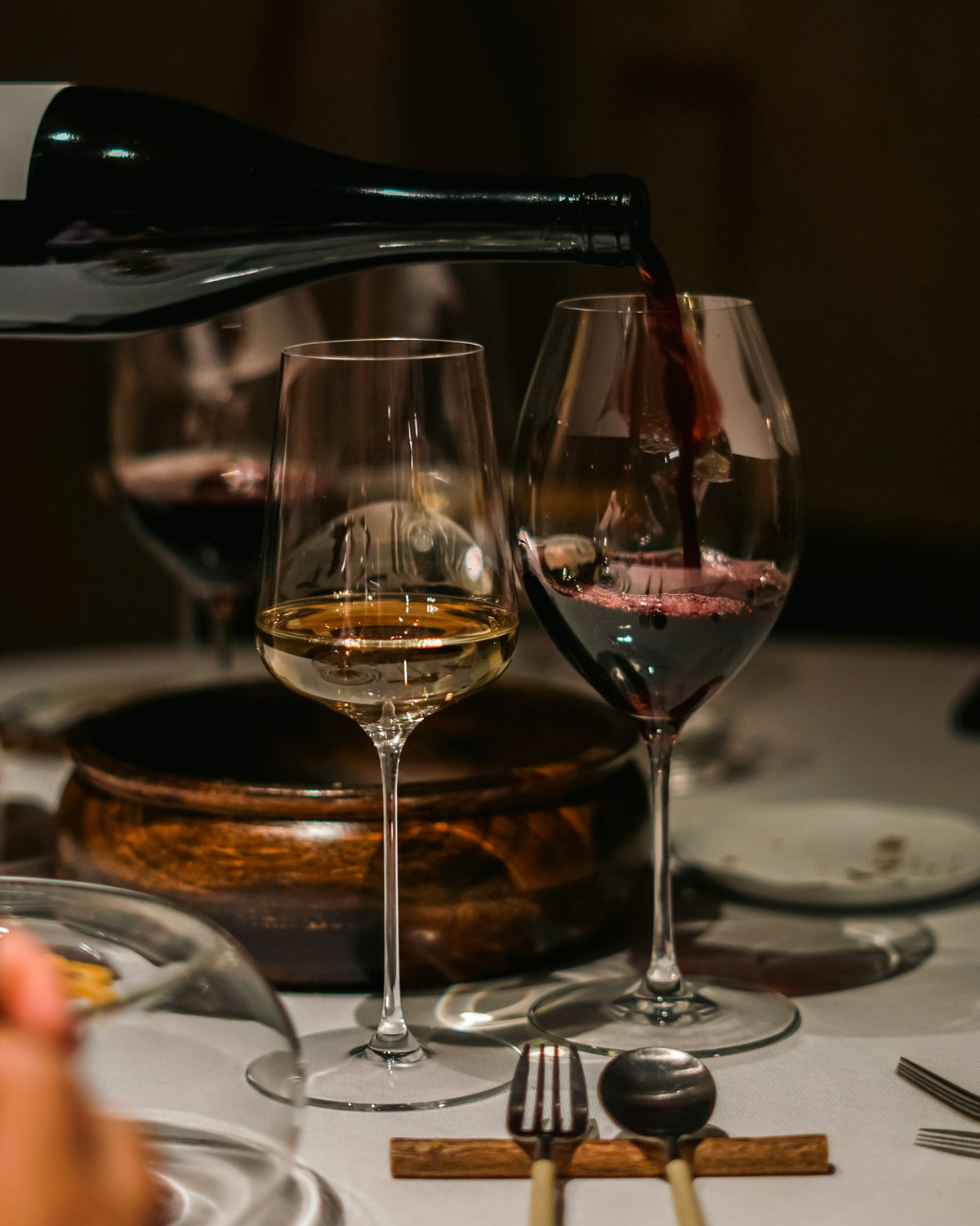 Wine poured at an intimate wooden dinner table