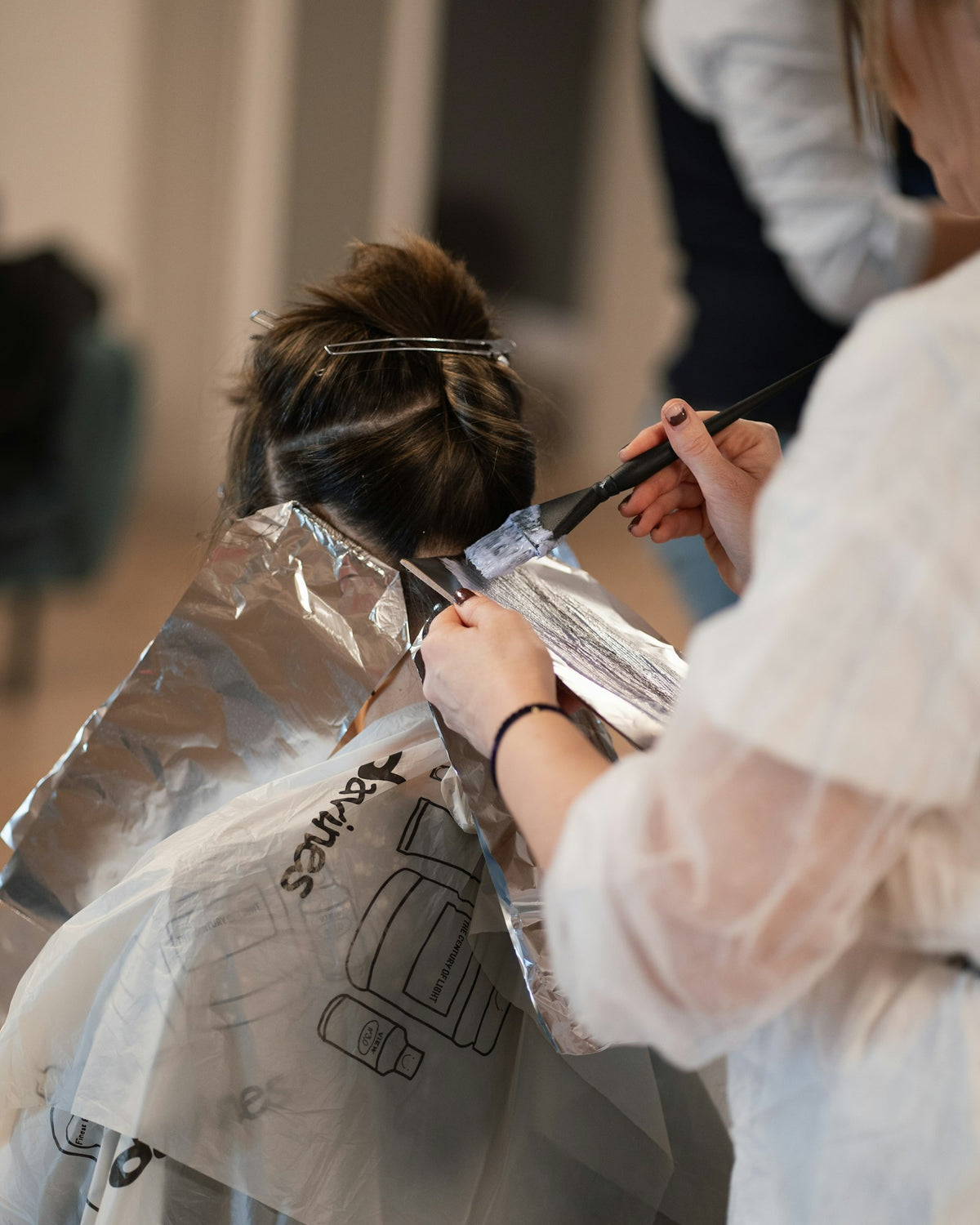 Colourist applying hair colour with foils