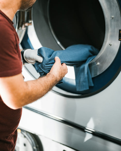 Hands at the open drum of a front-load washing machine