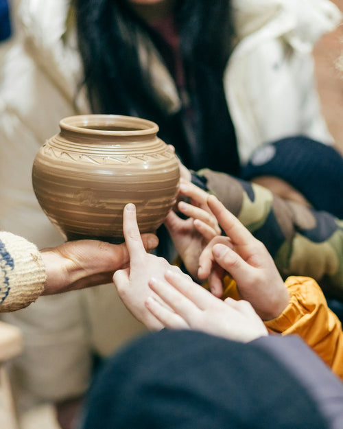 A group passing around a handmade clay pot