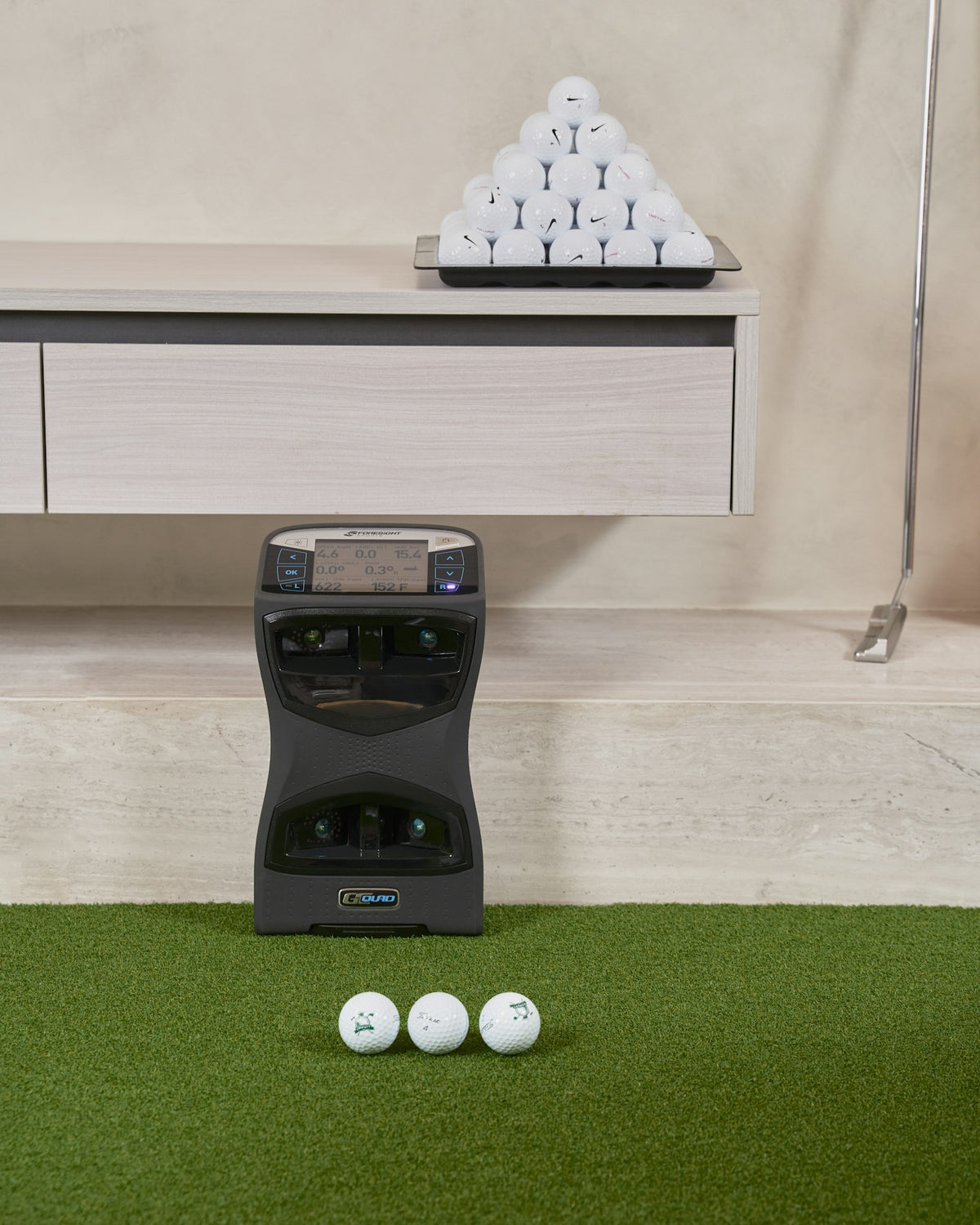 Indoor golf bay with a launch monitor and balls on green turf