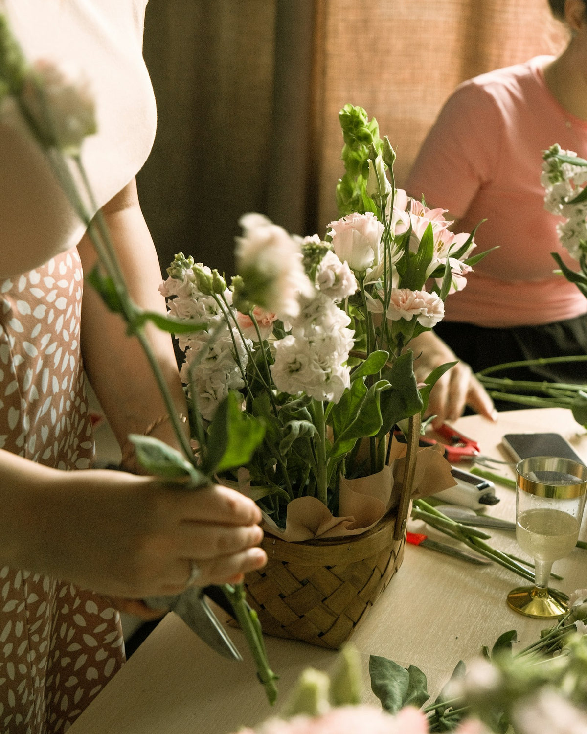 Woman arranging fresh flowers in a woven basket